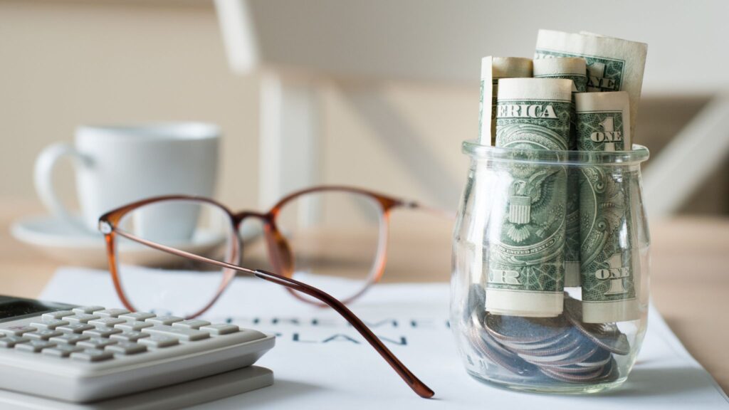 money jar and glasses on a desk
